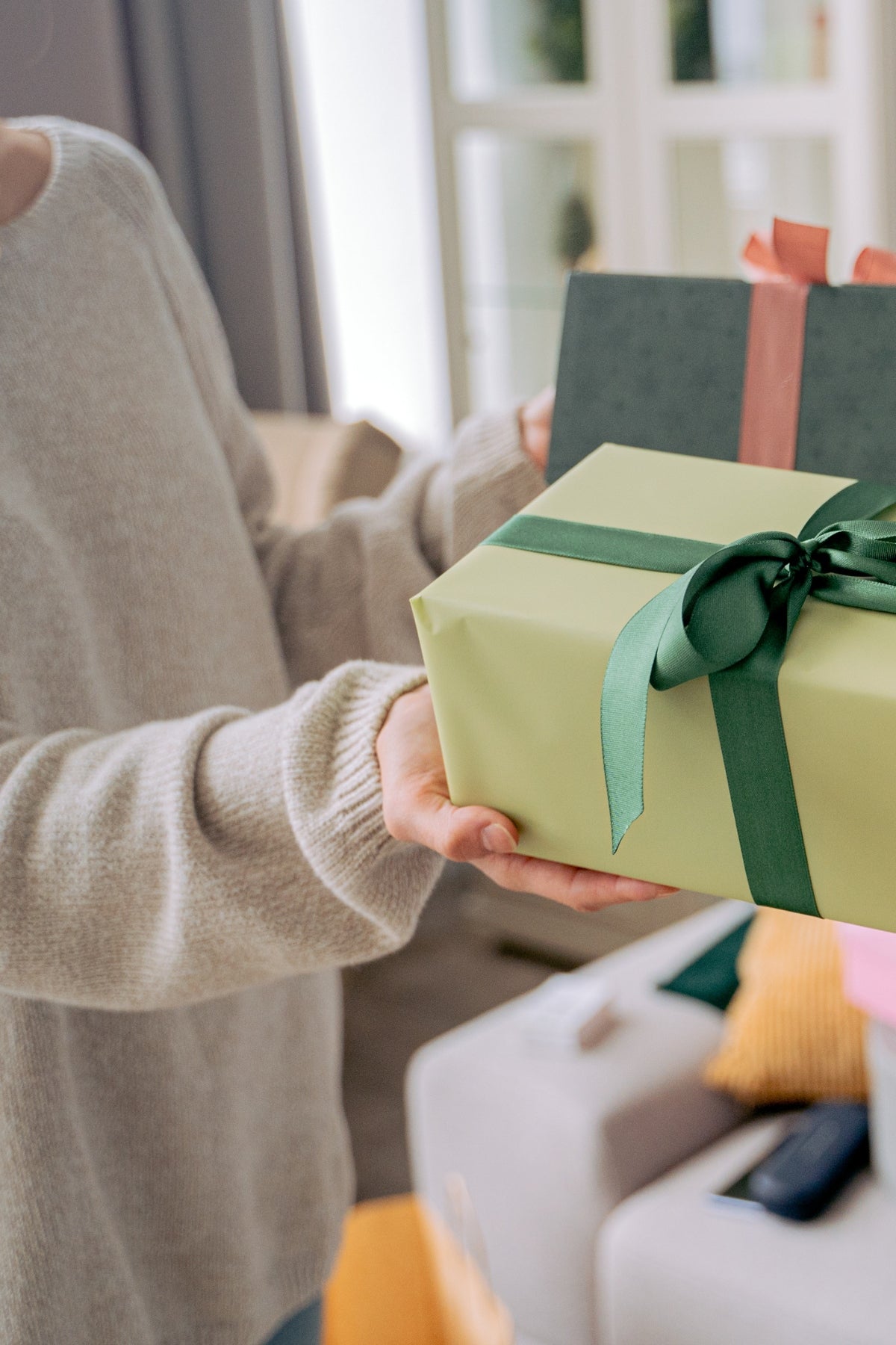 Woman with two gift boxes in front of a couch.