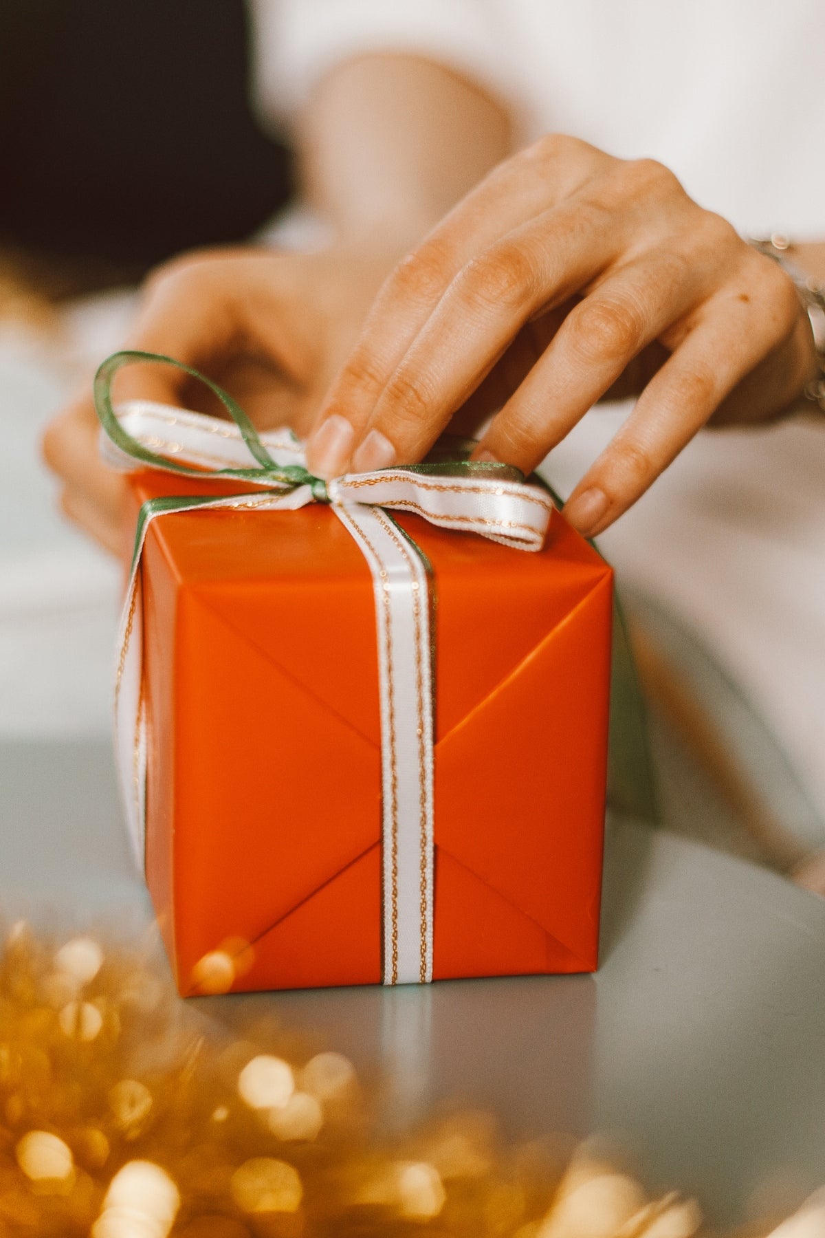 Person holding a red gift box on a table.