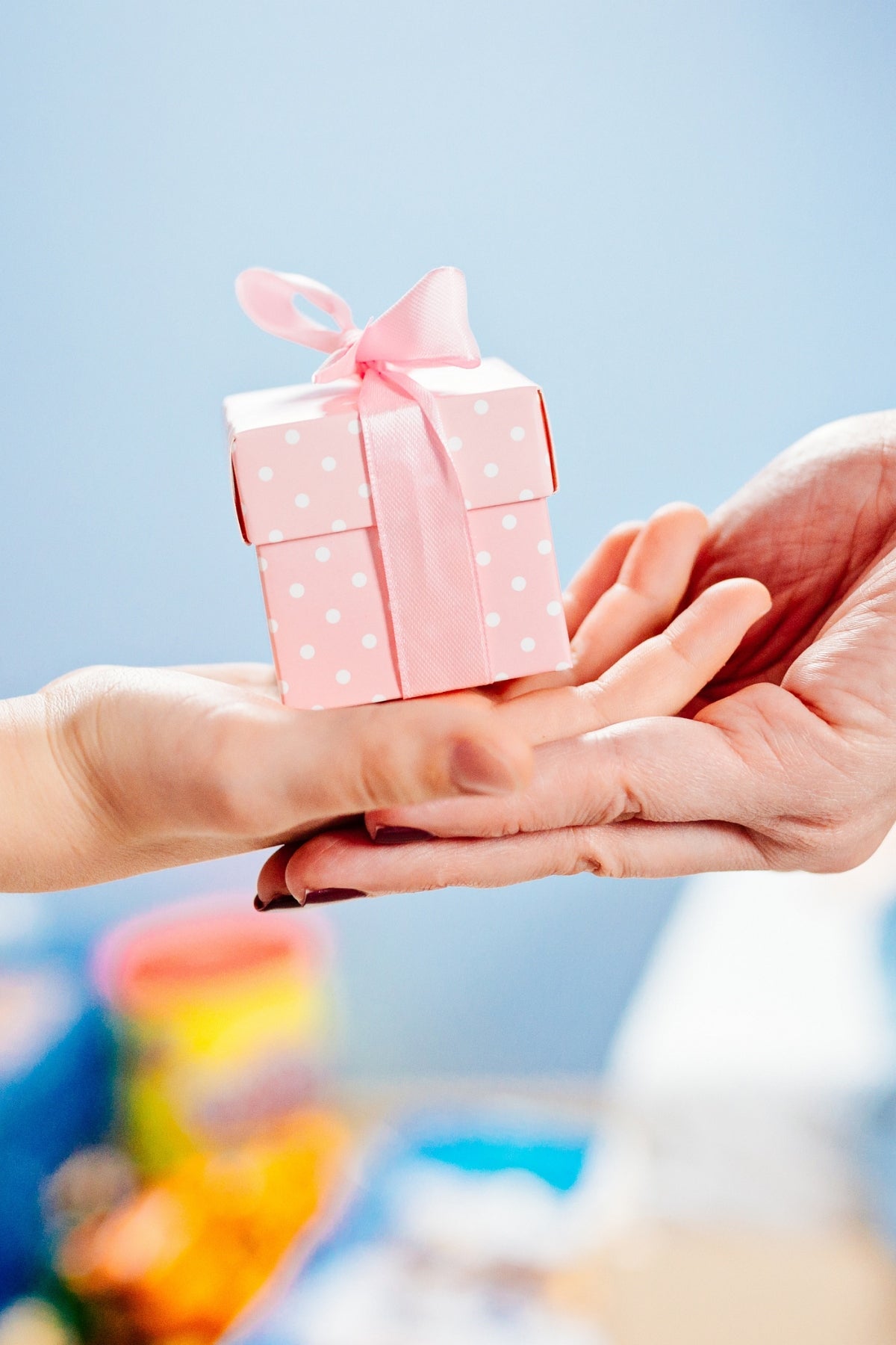 A hand presenting a pink gift box.