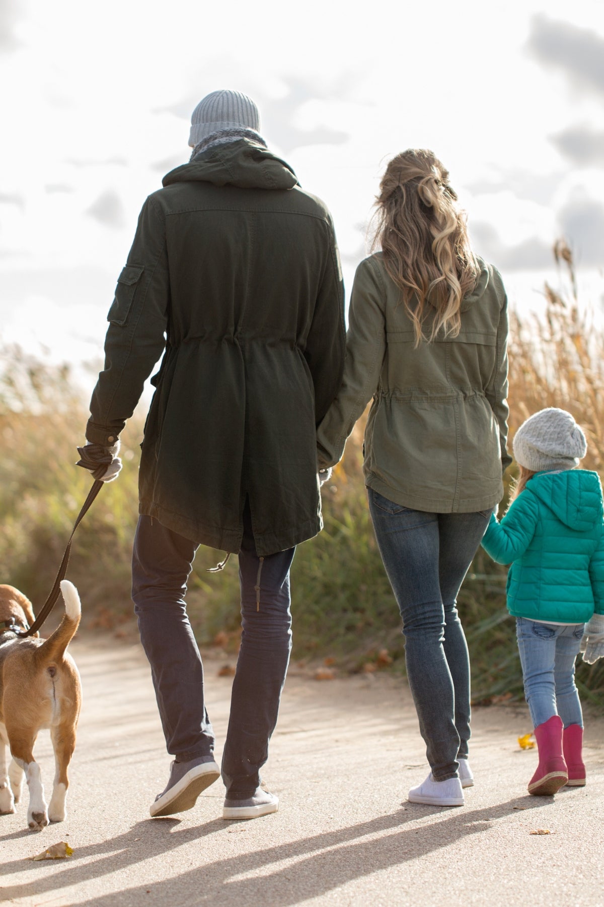 A family walking a dog with their child.