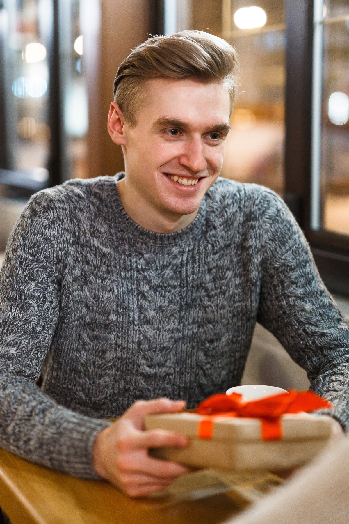 Smiling man holding a gift box joyfully.