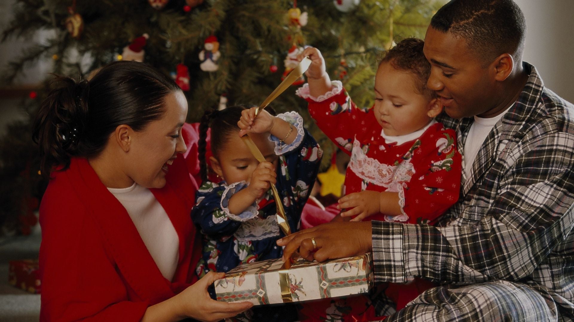 Family joyfully opening Christmas gift together.