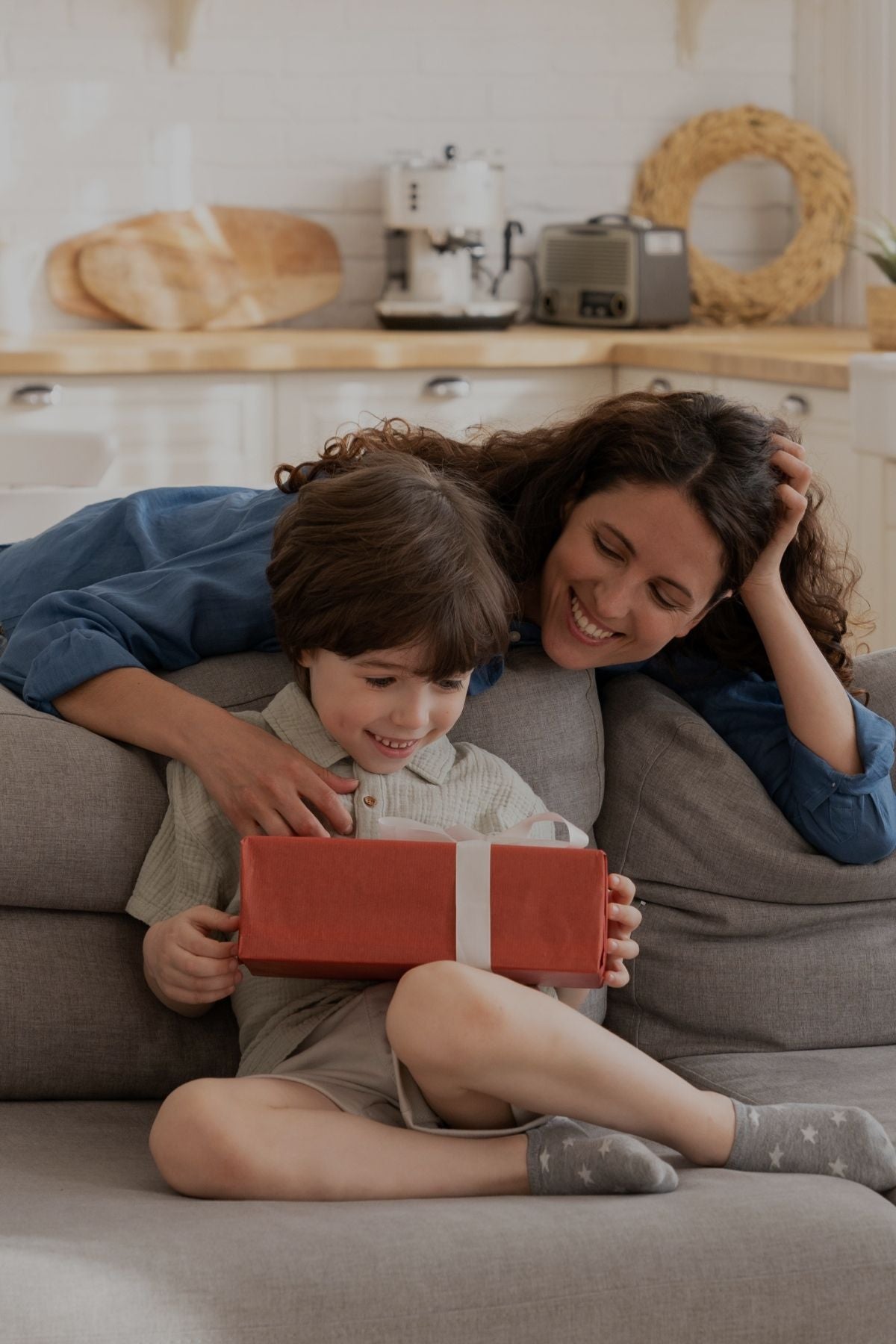 Woman and boy on couch with gift box.