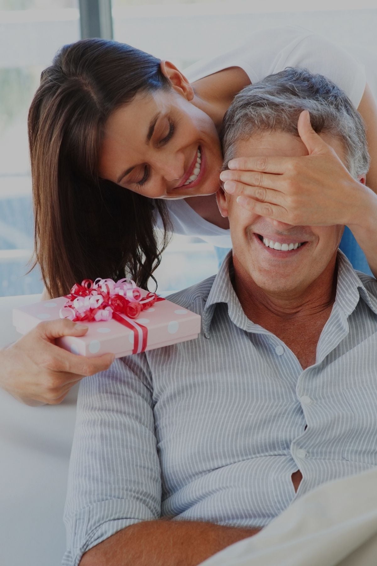 A smiling man and woman joyfully hold a gift, capturing a moment of celebration and happiness together