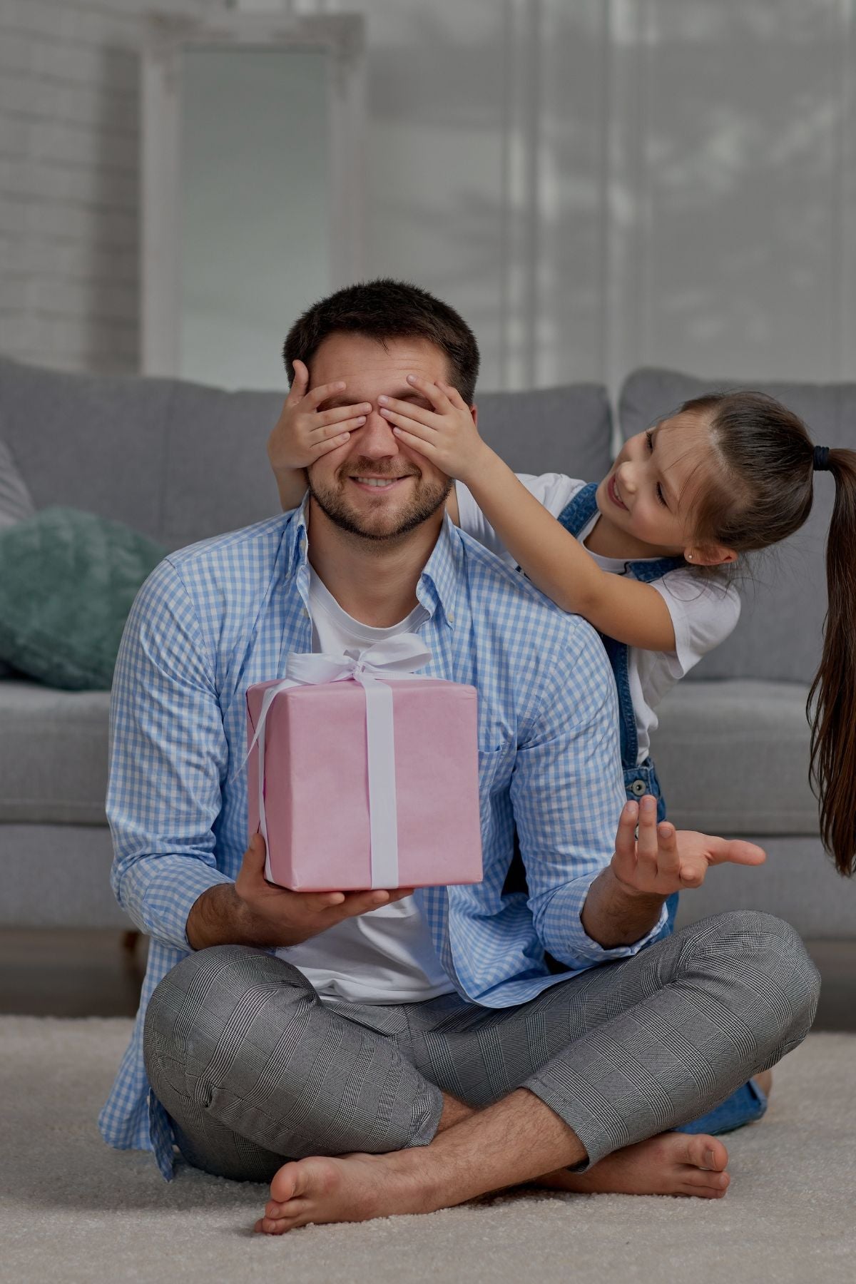 A joyful father and daughter share a moment in their living room, surrounded by a gift box, radiating happiness and love